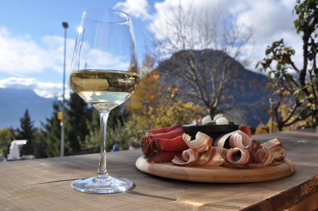 a glass of white wine next to a plate of food at Chez Tessa - Chambre double in Chamoson