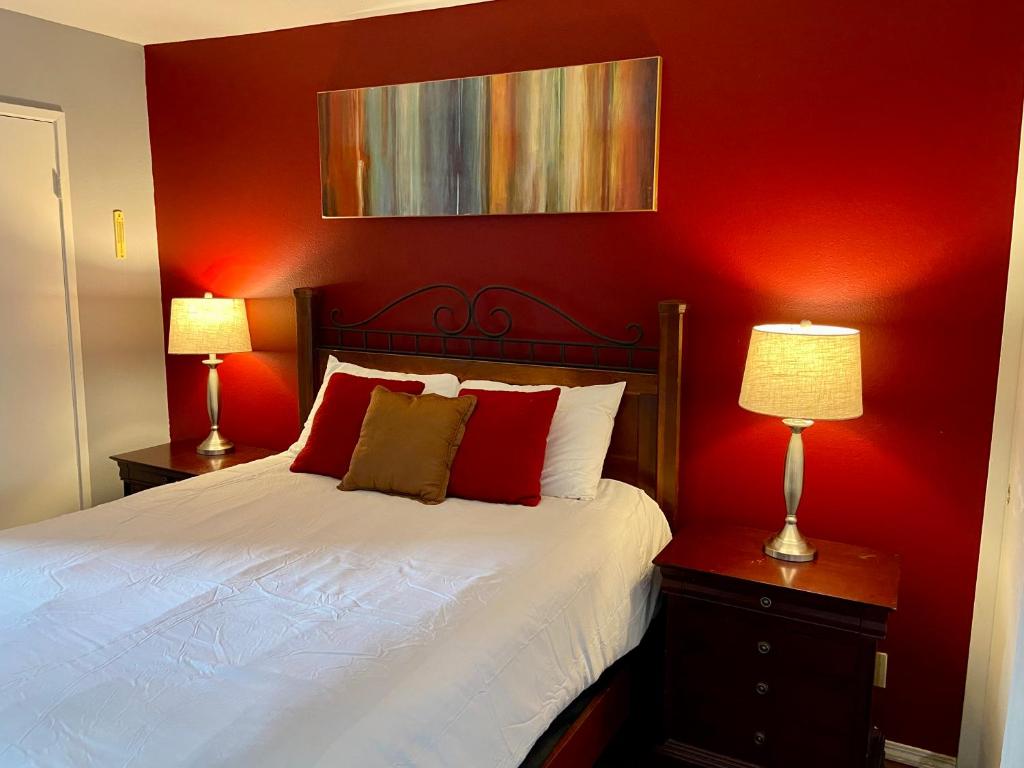 a bedroom with a bed with red walls and two lamps at Desert Getaway in Desert Hot Springs