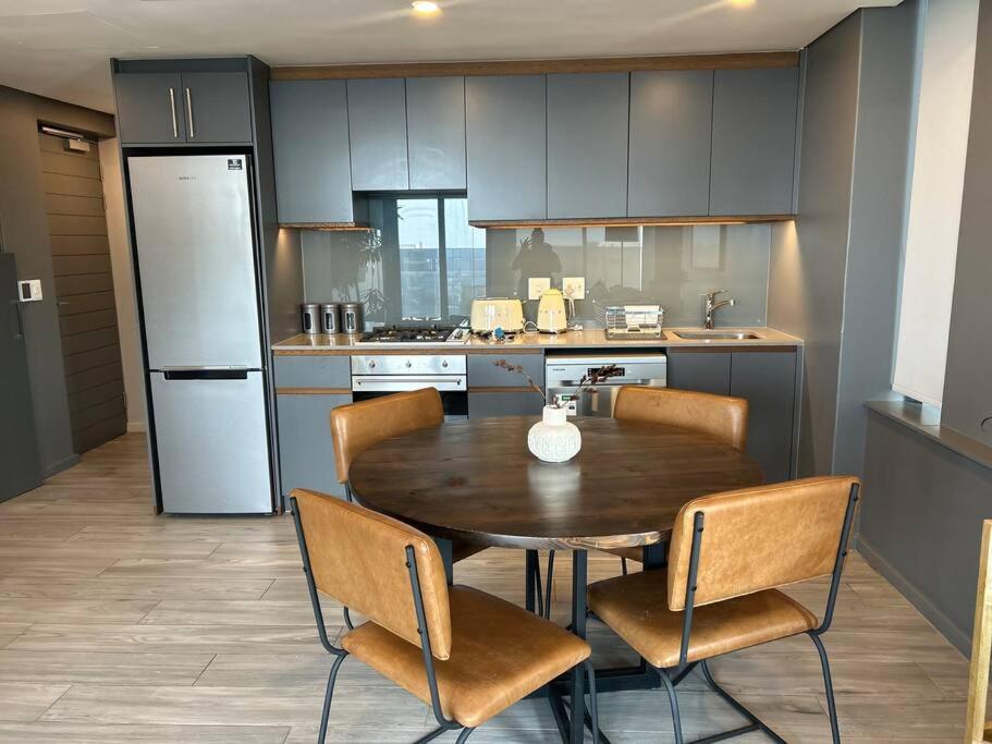 a kitchen with a wooden table and chairs and a refrigerator at Umhlanga Arch Sea View Apartment in Durban