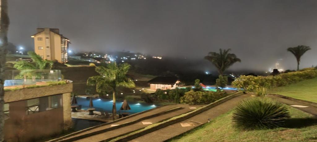 vista para uma piscina num resort à noite em APARTAMENTO BANANEIRAS - SONHOS DA SERRA BLOCO E em Bananeiras