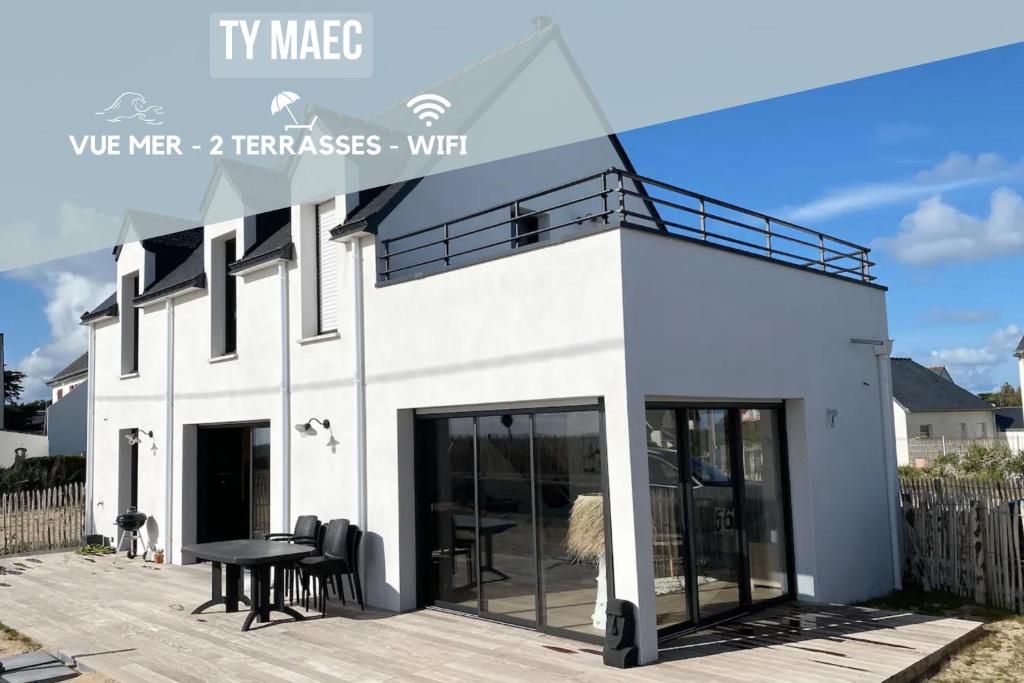 une maison blanche avec des portes en verre sur une terrasse dans l'établissement Ty Maec - Maison vue mer - Idéale pour le surf, kitesurf et la détente, à Saint-Pierre-Quiberon