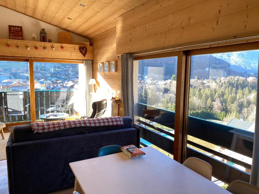 un salon avec un canapé et une grande fenêtre dans l'établissement Luxury Apartment, 350m to ski lift, south facing, close to town centre, à Morzine