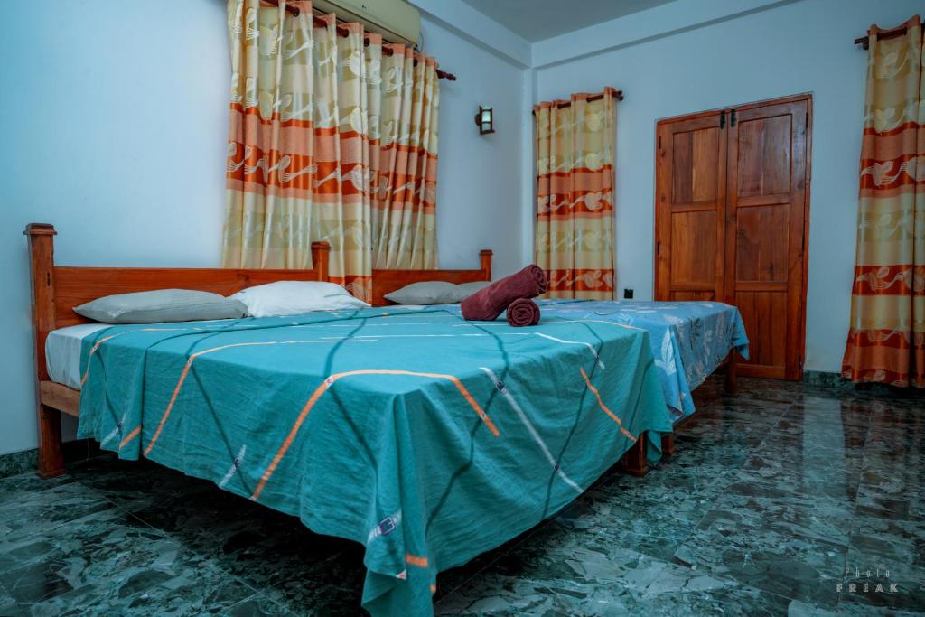 a bedroom with a bed with a blue comforter at Hotel Athina & Restaurant in Chilaw