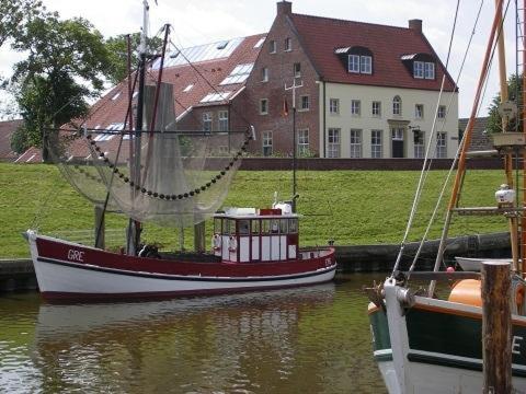 a boat is docked in the water next to a house at *Willems - Amtmannshaus Hauen in Greetsiel