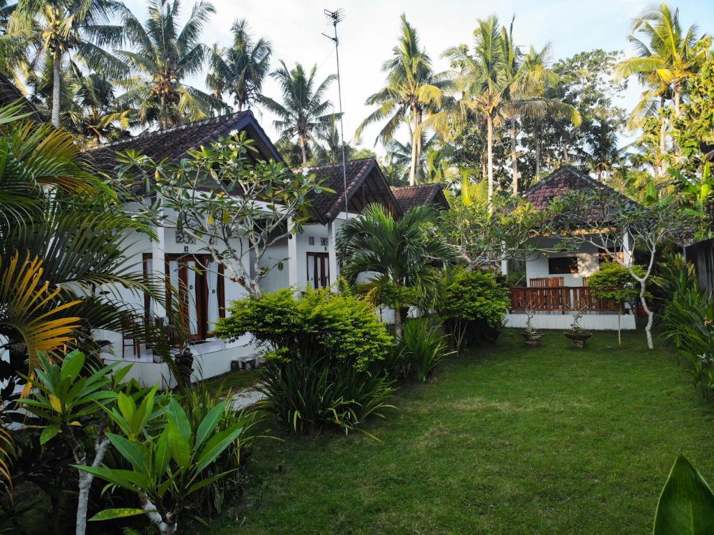 a white house with palm trees and a yard at Kubu Indah Guest House in Nusa Penida