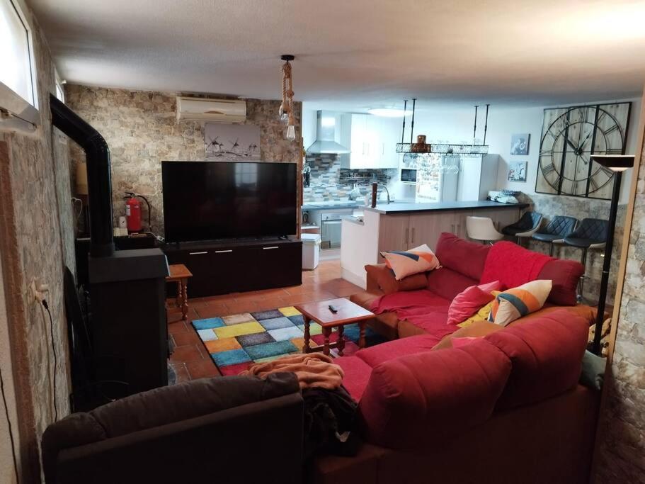 a living room with a red couch and a kitchen at La casa de Gloria in Cúllar-Vega