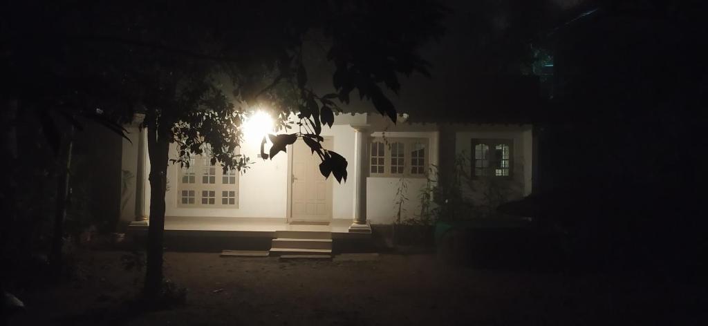 una casa blanca con una luz en la puerta por la noche en Leeland Munnar, en Munnar