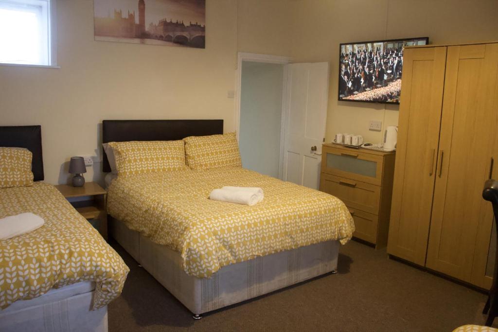 een slaapkamer met 2 bedden en een dressoir bij Elm Tree Guest House in Weston-super-Mare