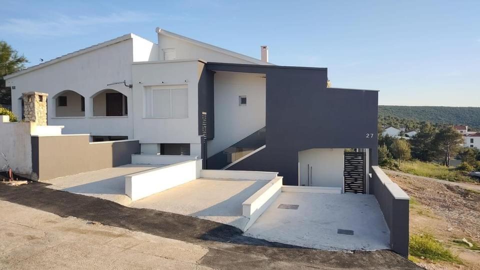 a white house with a garage and a driveway at Apartman Mate in Novigrad Dalmatia