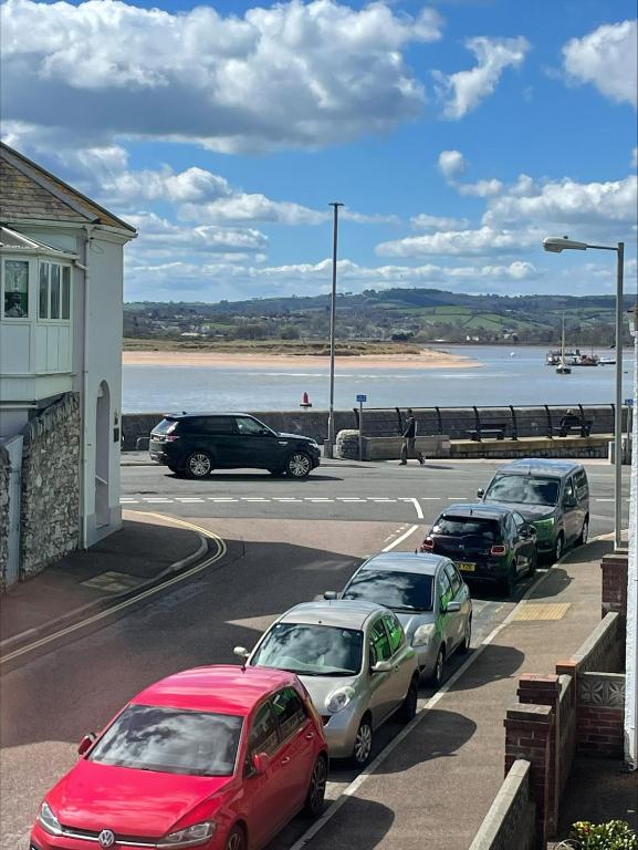 a row of cars parked in a parking lot next to a beach at Seaview Apartment with parking in Exmouth