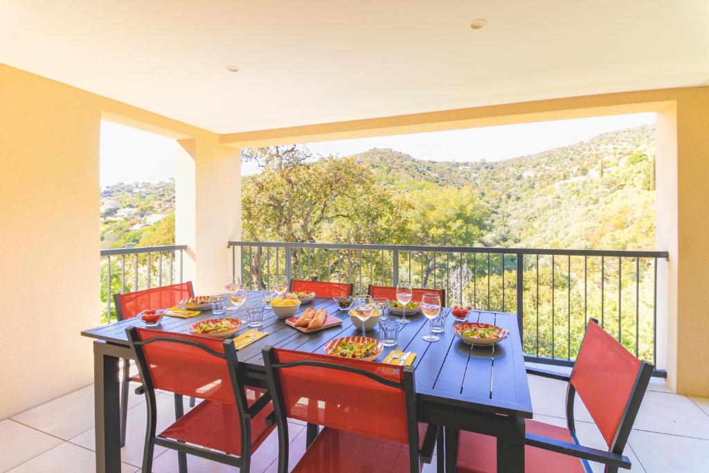 un balcon avec une table bleue et des chaises rouges dans l'établissement Villa entre Rose et Pins à Bormes-les-mimosas 4 étoiles - ROSES&PINS, à Bormes-les-Mimosas