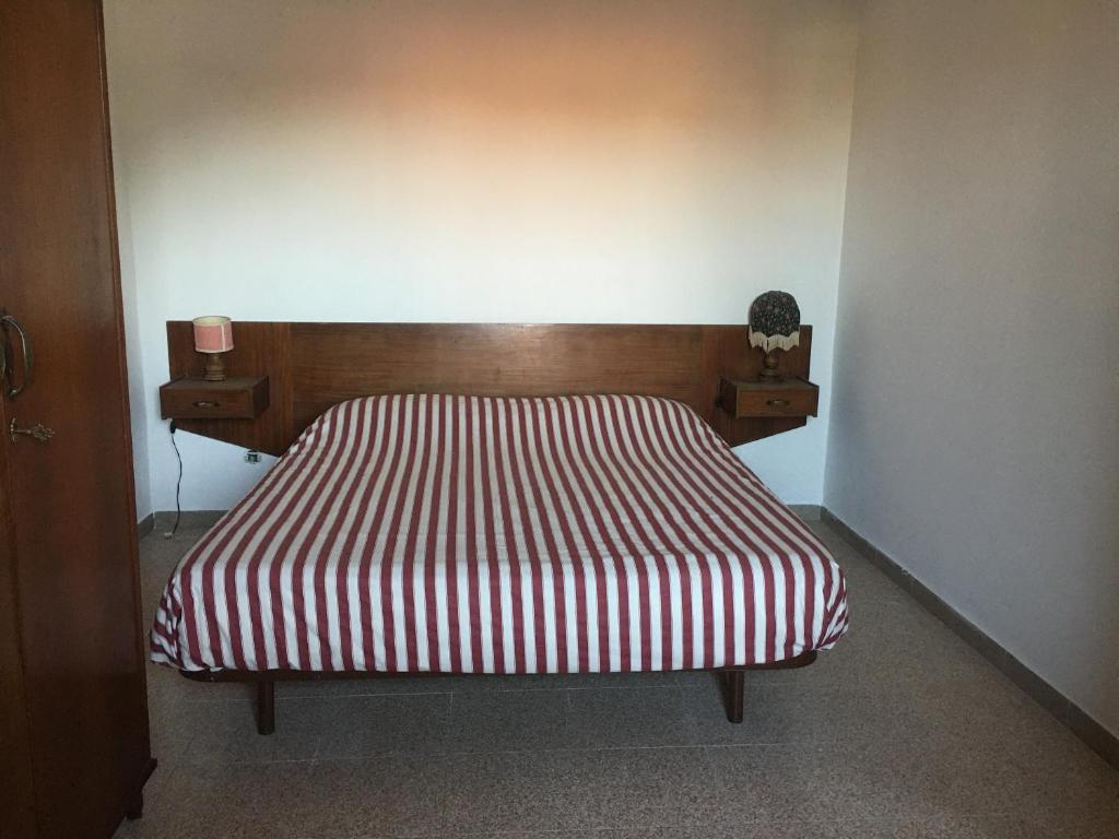 ein Bett mit einer rot-weißen gestreiften Decke in einem Zimmer in der Unterkunft Casetta indipendente al lago di Bolsena in Valentano