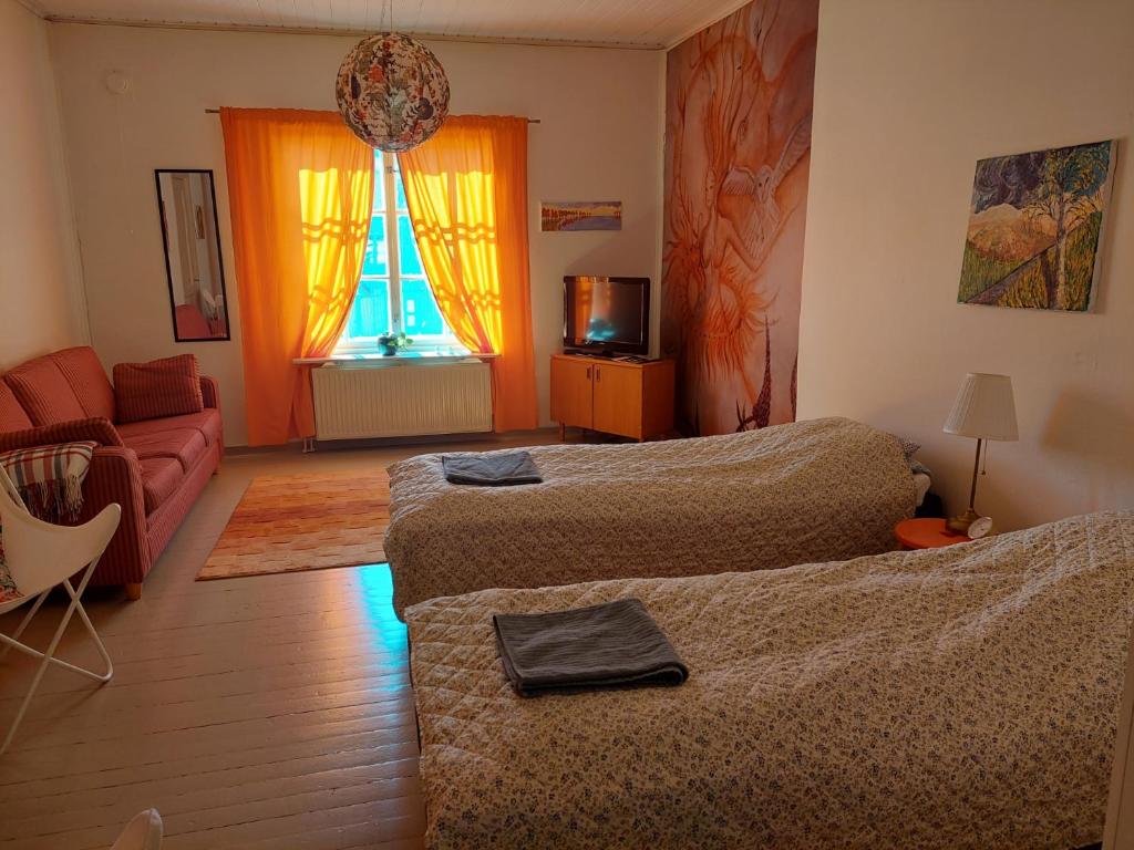 een slaapkamer met 2 bedden, een bank en een raam bij Nostalgista majoittumista Taiteilijatalo Taideniityn Auringossa tai Niityssä in Varkaus