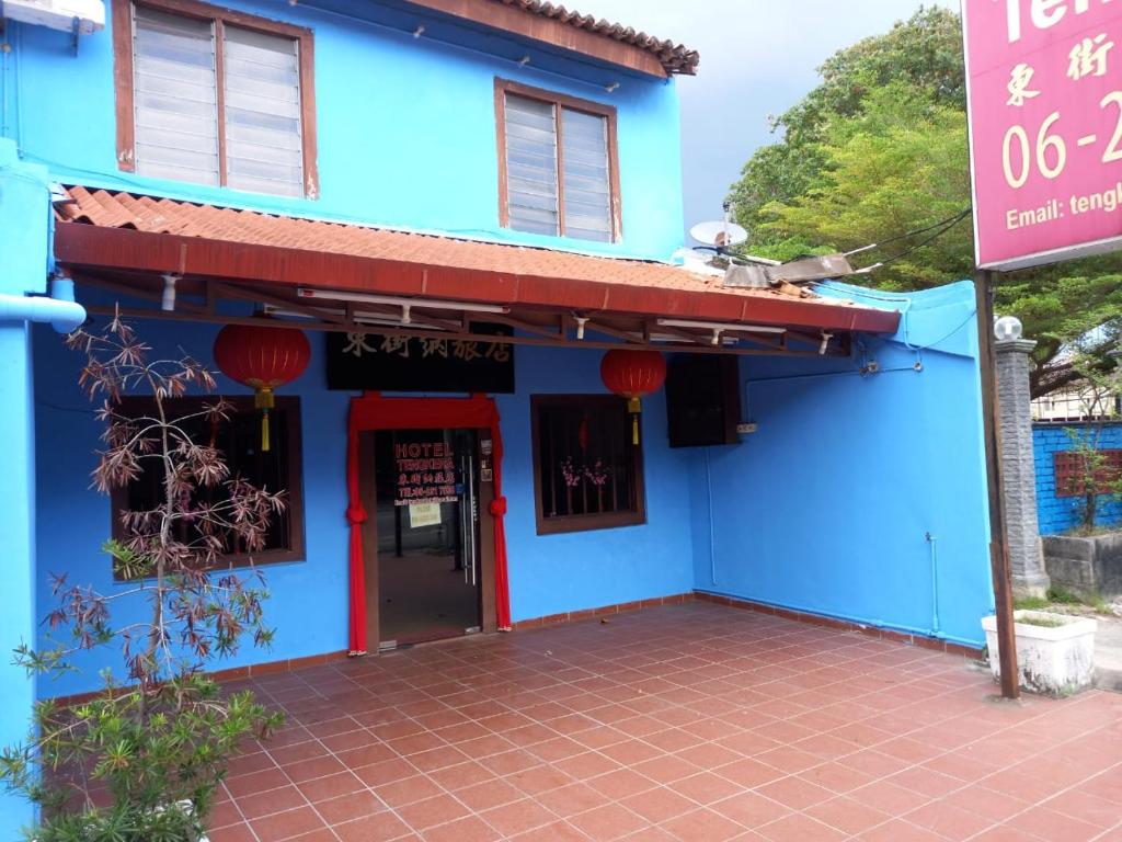 ein blaues Gebäude mit einer roten Tür in der Unterkunft Tengkera Hotel in Malakka