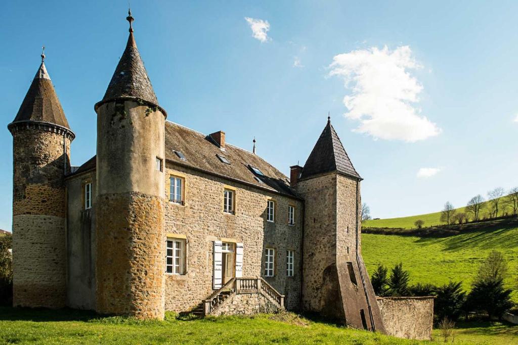 un antiguo castillo con dos torres en un campo verde en Château de Sainte Colombe sur Gand en Sainte-Colombe-sur-Gand
