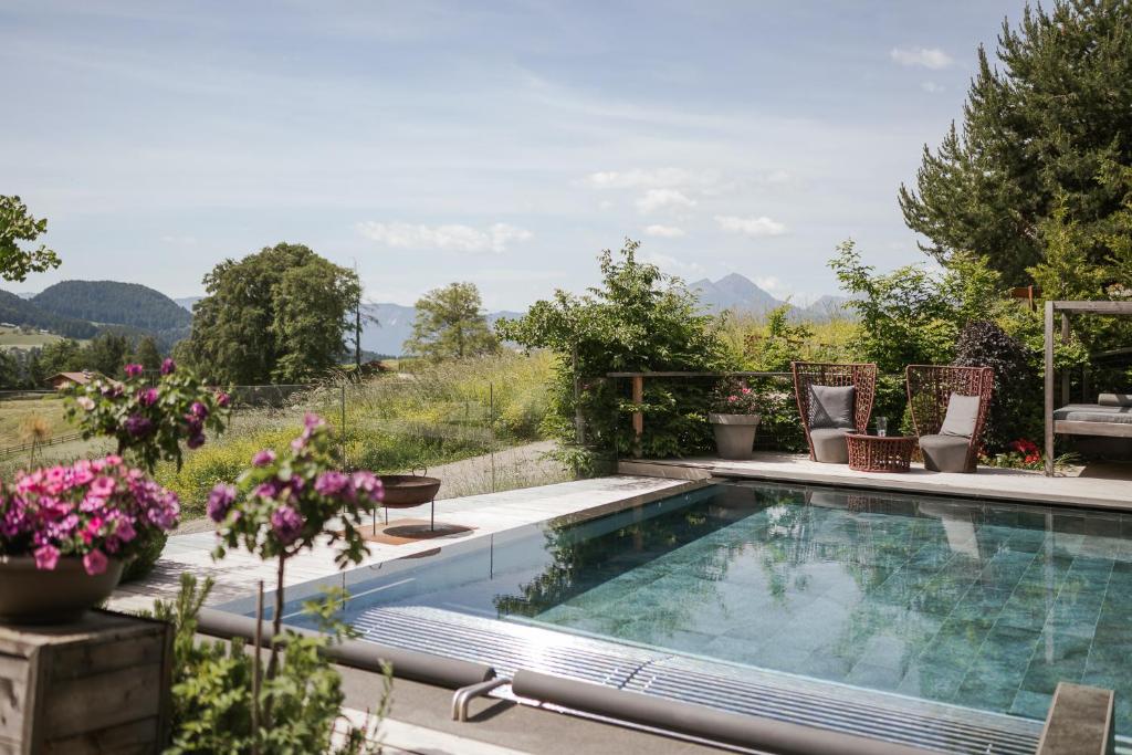 a swimming pool in a garden with flowers at Hotel Hirzer 2781 in Avelengo