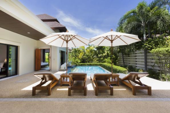 une terrasse avec des chaises et des parasols ainsi qu'une piscine dans l'établissement Residence Lake Rawai, à Phuket