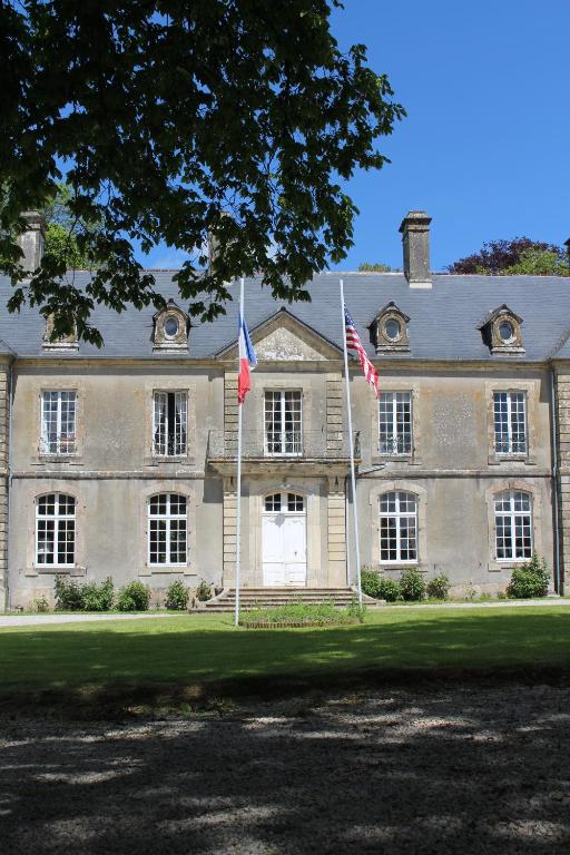 una grande casa con due bandiere davanti di Château de Grandval - Sainte Mere Eglise a Neuville-au-Plain
