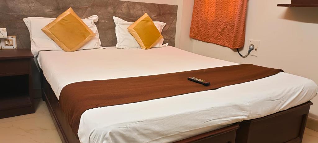 a bed with yellow pillows and a remote control on it at CENTRAL GATE in Chennai