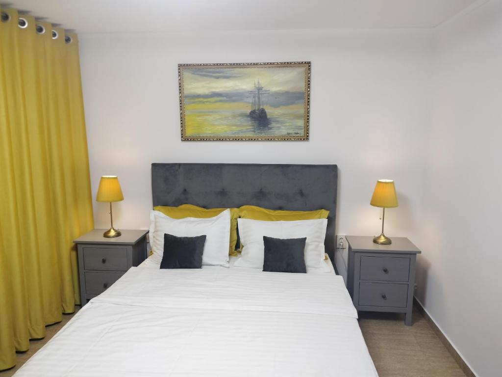 - une chambre avec un grand lit blanc et 2 tables de chevet dans l'établissement Apartament Faleza Nord, à Constanţa