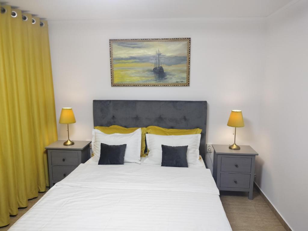 a bedroom with a large white bed with two night stands at Apartament Faleza Nord in Constanţa