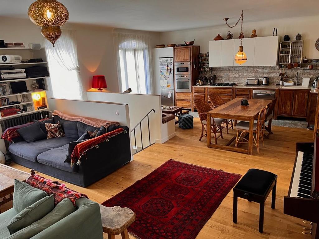 ein Wohnzimmer und eine Küche mit einem Sofa und einem Tisch in der Unterkunft Maison de charme à Montreuil, à 10mn de Paris in Montreuil