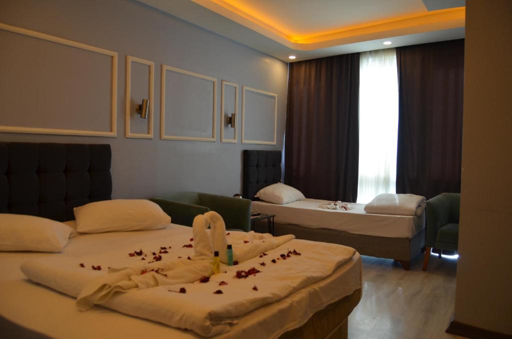 a hotel room with two beds with rose petals on them at Coisin Royal Hotel in Arnavutköy