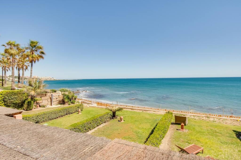 a view of the ocean with palm trees and the beach at Beachfront Townhouse Estepona in Estepona