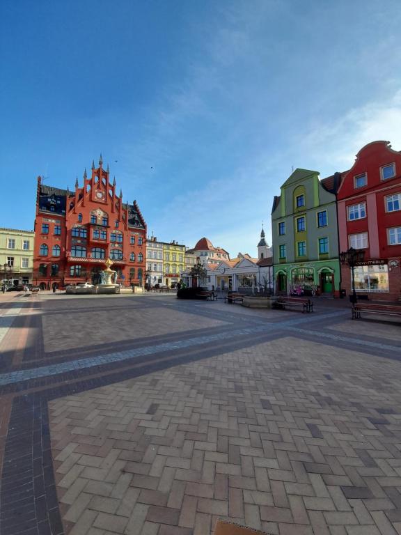 una plaza de la ciudad con edificios coloridos y una calle adoquinada en Pokoje Gościnne FABIO, en Chojnice