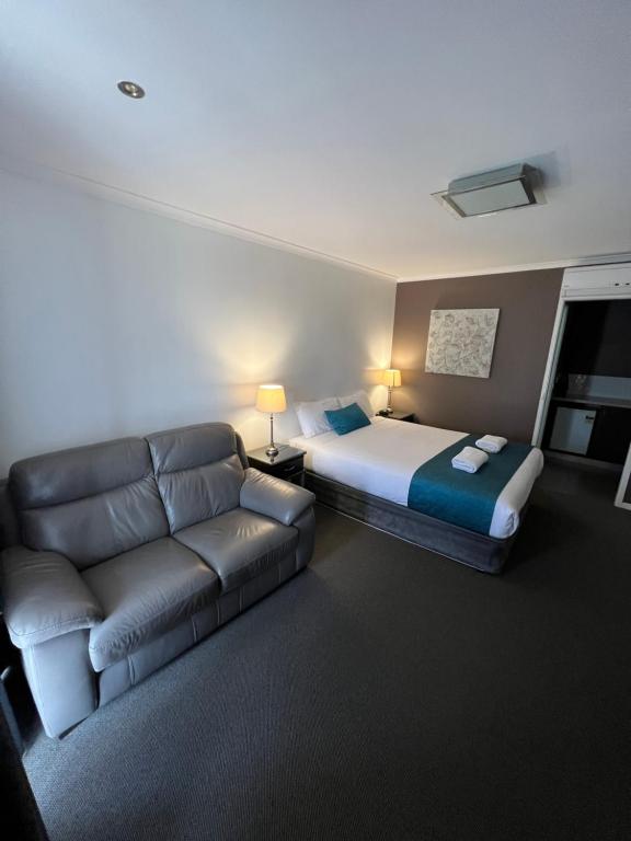 ein Hotelzimmer mit einem Bett und einem Sofa in der Unterkunft Pevensey Motor Lodge in Echuca