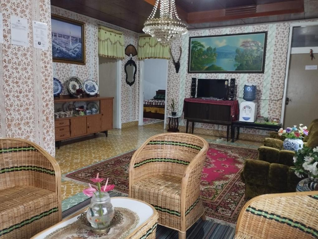 uma sala de estar com cadeiras de vime e uma mesa em Mando Homestay II em Bukittinggi