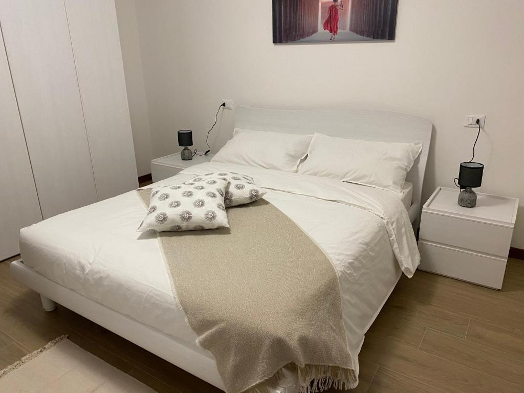 um quarto com uma cama com lençóis brancos e almofadas em Residence Antonio Vivaldi em Noventa di Piave