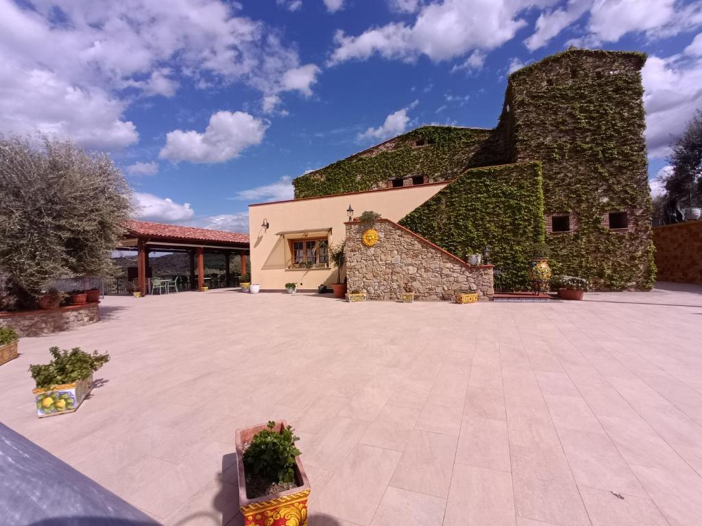 a large courtyard with a building covered in ivy at Agriturismo le Campanelle - Sicilia - Cefalù in Lascari