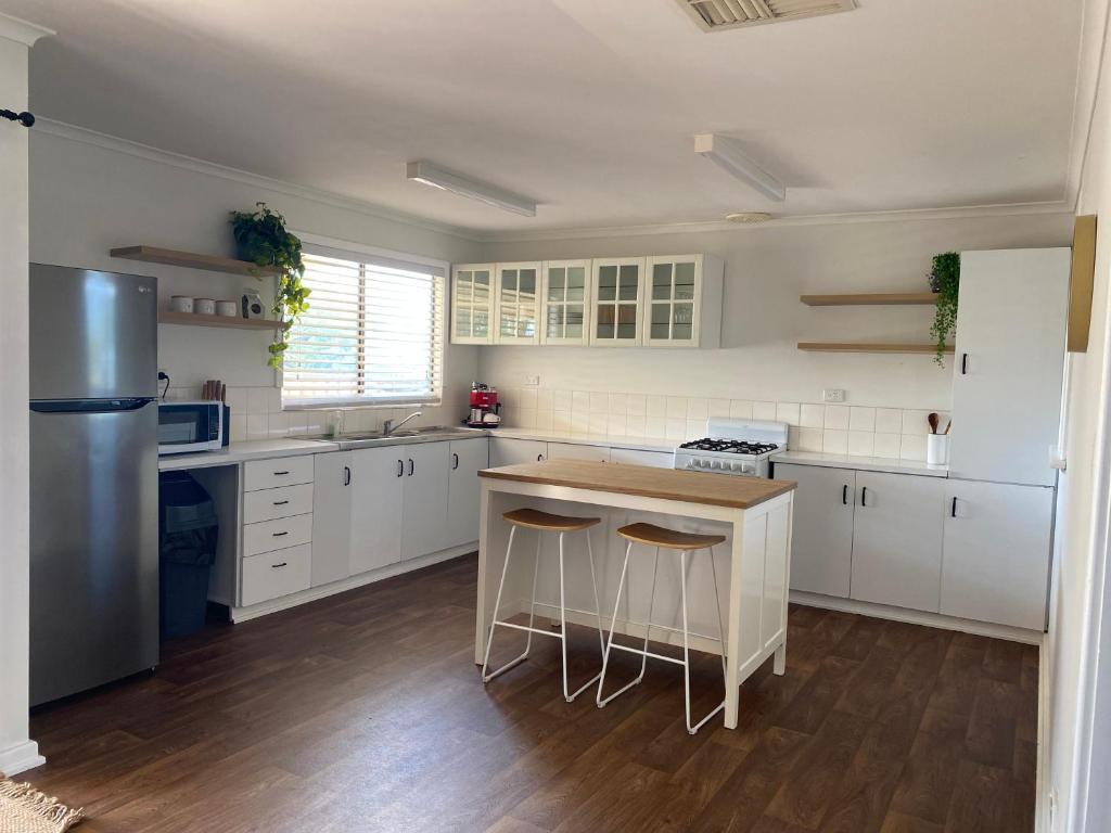 una cocina con armarios blancos y una isla de cocina con taburetes en Country retreat, 