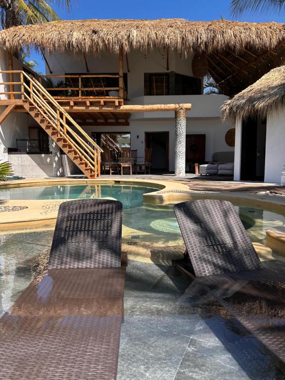 two chairs sitting in front of a house with a swimming pool at Villa Bamboo in Coyuca