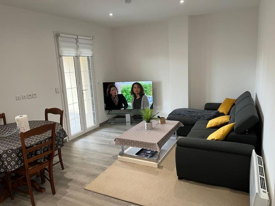 a living room with a black couch and a tv at House with terrace près de l'Aéroport RoissyCDG - Tour Eiffel - Champs Elysée - Paris - Aéroville centre commercial - Parc Astérix - Disneyland Paris - Mer de sable - Châteaux de Chantilly et Ecouen - Parc des expositions Villepinte - Le Bourget in Le Thillay
