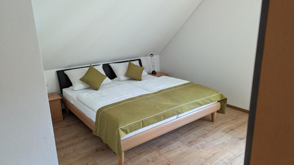 una camera da letto con un letto con lenzuola bianche e cuscini gialli di Ferienwohnungen Lehnerwirt a Breitenbrunn