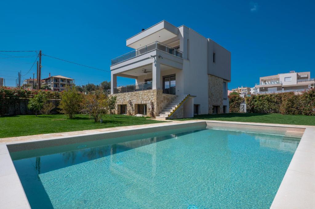 a villa with a swimming pool in front of a house at Sea Wind Luxury Villa with Private Heated Pool Kassandra Halkidiki in Nea Fokea