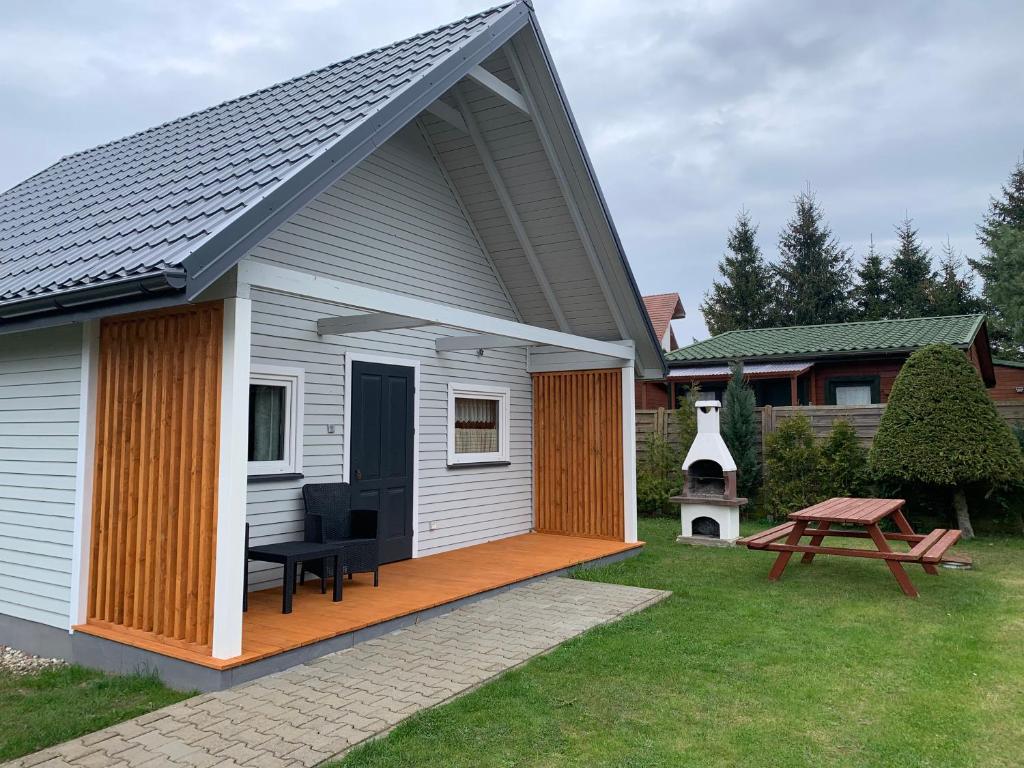 a small white house with a porch and a picnic table at Dom Gościnny & Domki Letniskowe EDYTA in Rewal