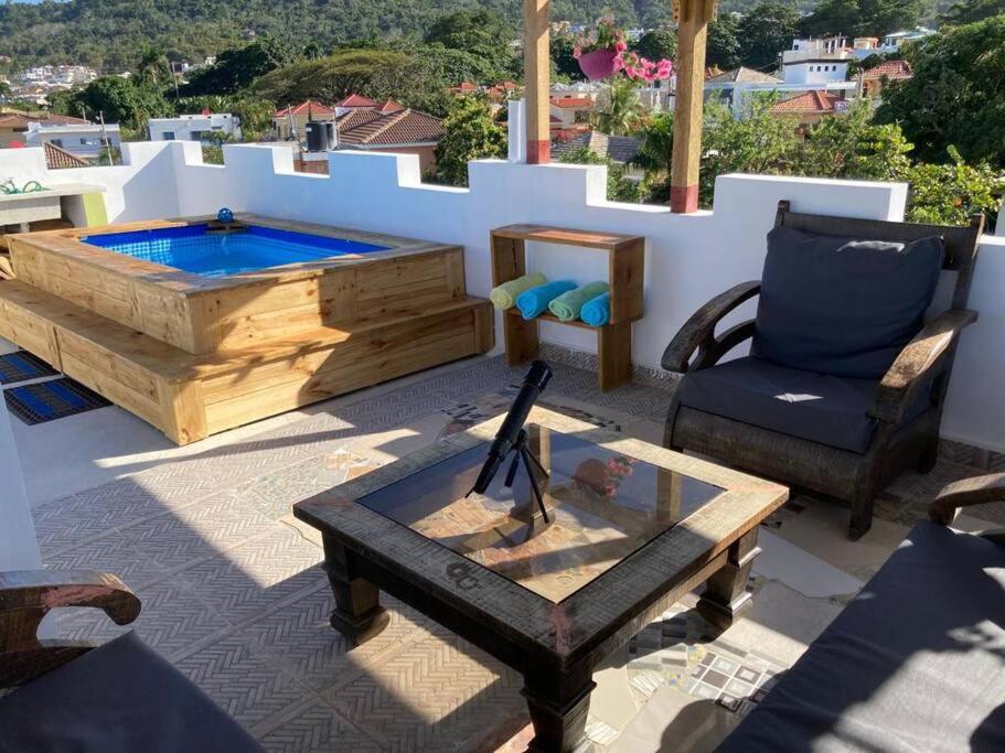 a patio with a hot tub and a table and chairs at Tropical Inn Spacious 1 bed Apartment stunning rooftop terrace in San Felipe de Puerto Plata