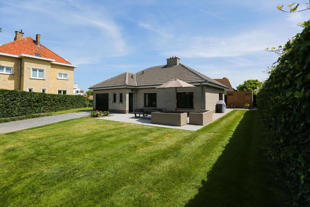 una casa con césped delante de una casa en Casa Dunas, en Middelkerke