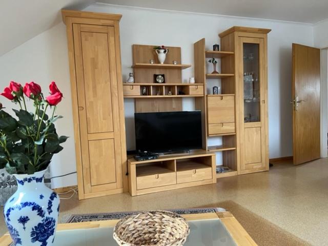 a living room with a tv and a vase with roses at Ferienwohnung Neetze in Neetze