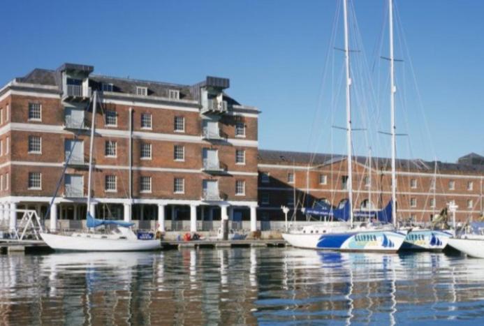 un grupo de barcos atracados frente a un edificio en Beautiful Marina Apartment with private garden, flexible bedrooms with zip & link beds, en Gosport