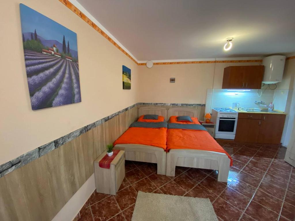 um quarto com 2 camas com lençóis laranja em Hajnal Apartman em Hajdúszoboszló