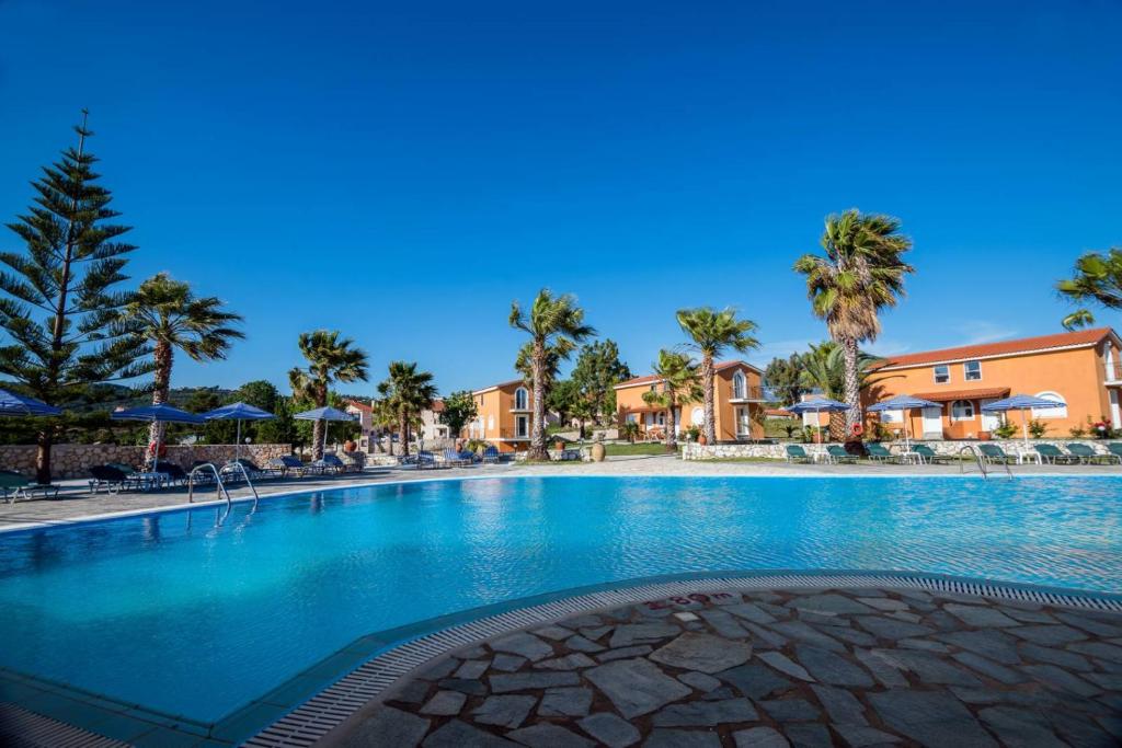 a swimming pool at a resort with palm trees at Βessie's Village in Kefallonia