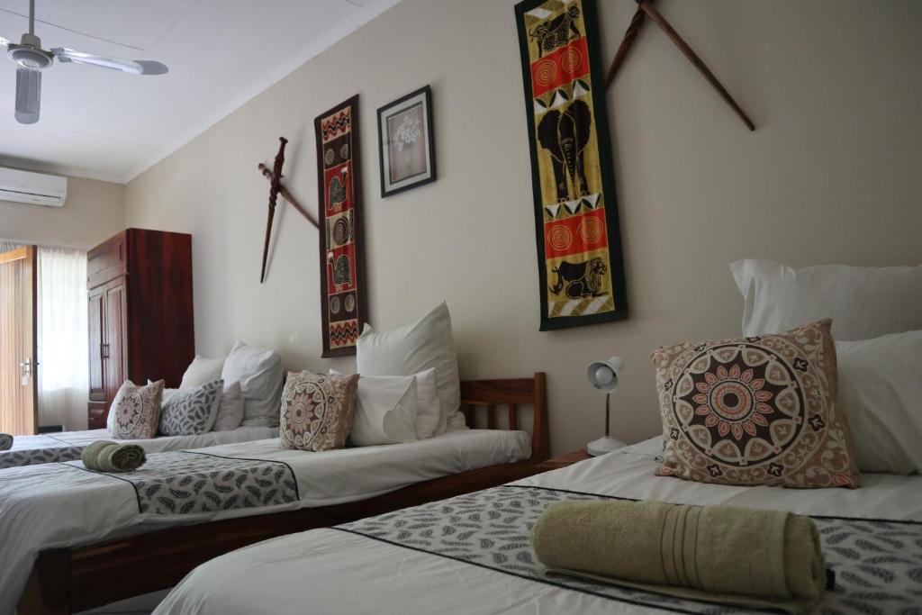 a room with three beds and paintings on the wall at Guest House Bavaria in Rundu