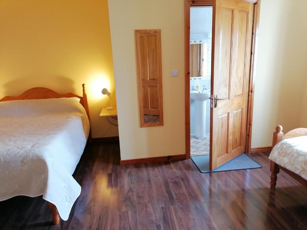 a bedroom with a bed and a door to a bathroom at Danubio Guest Accommodation in Doonbeg