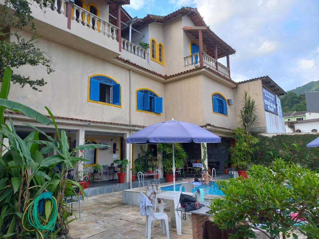 a house with a swimming pool and an umbrella at Pousada do Sossego Conceição de Jacareí in Mangaratiba