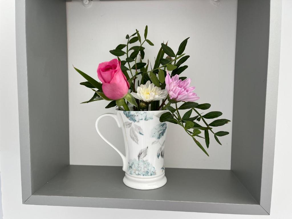 a vase filled with pink flowers sitting on a shelf at Whitstable The Jolly in Whitstable