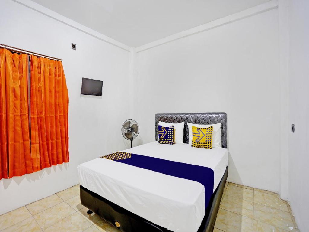 um quarto branco com uma cama com cortinas cor de laranja em SPOT ON 92452 Griya Sandi Homestay Syariah em Banyuwangi